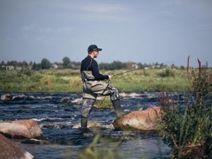 Рыболов в полукомбинезоне на реке